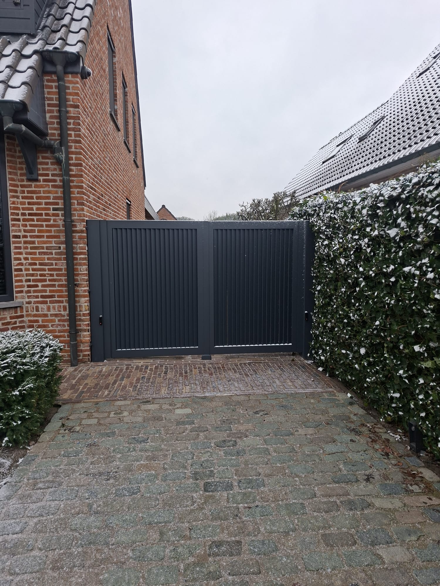Antraciet verticale draaipoort in de winter