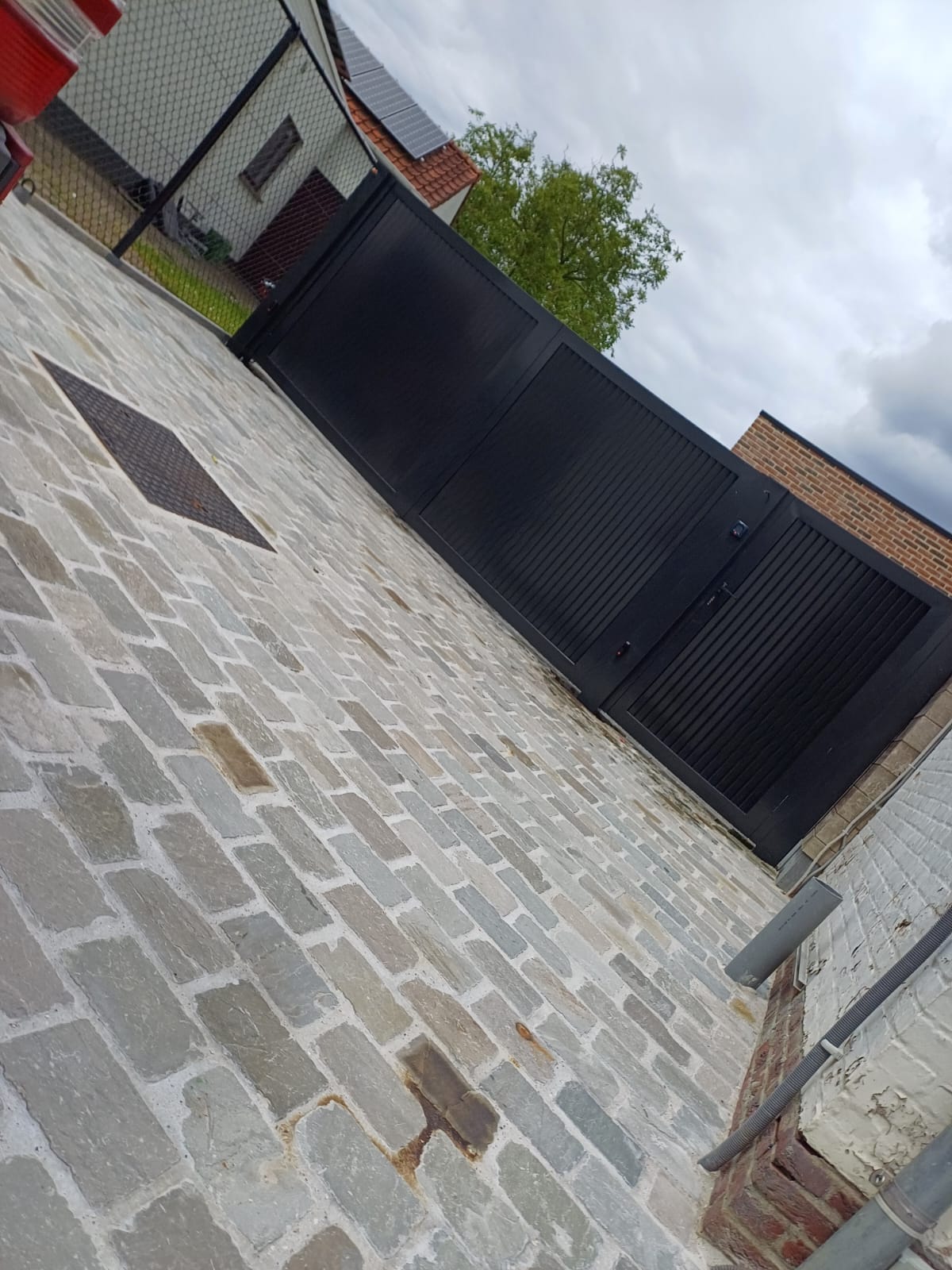 Moderne draaipoort in mat zwart op kasseien