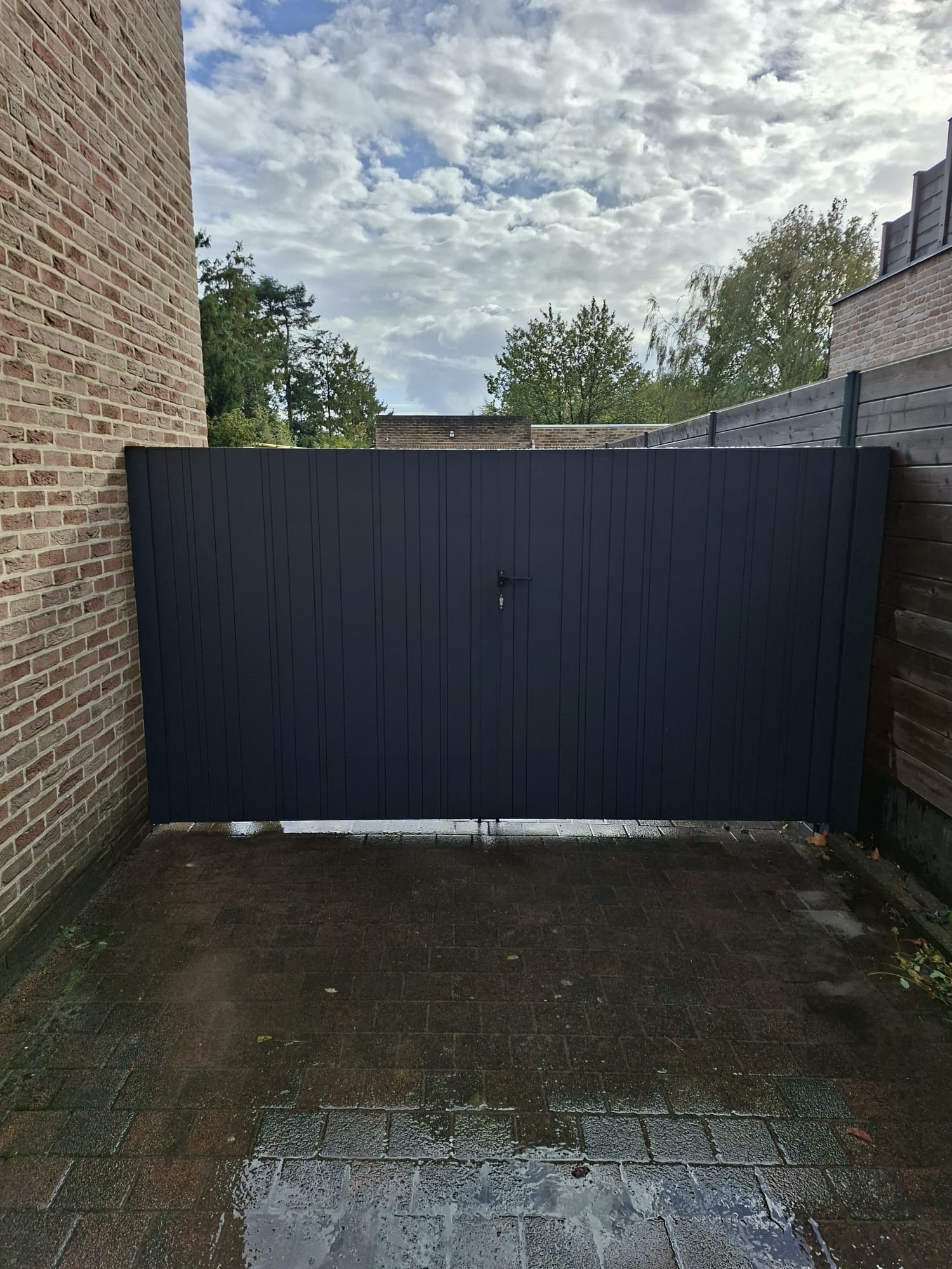 Antraciet poort tussen bakstenen muren