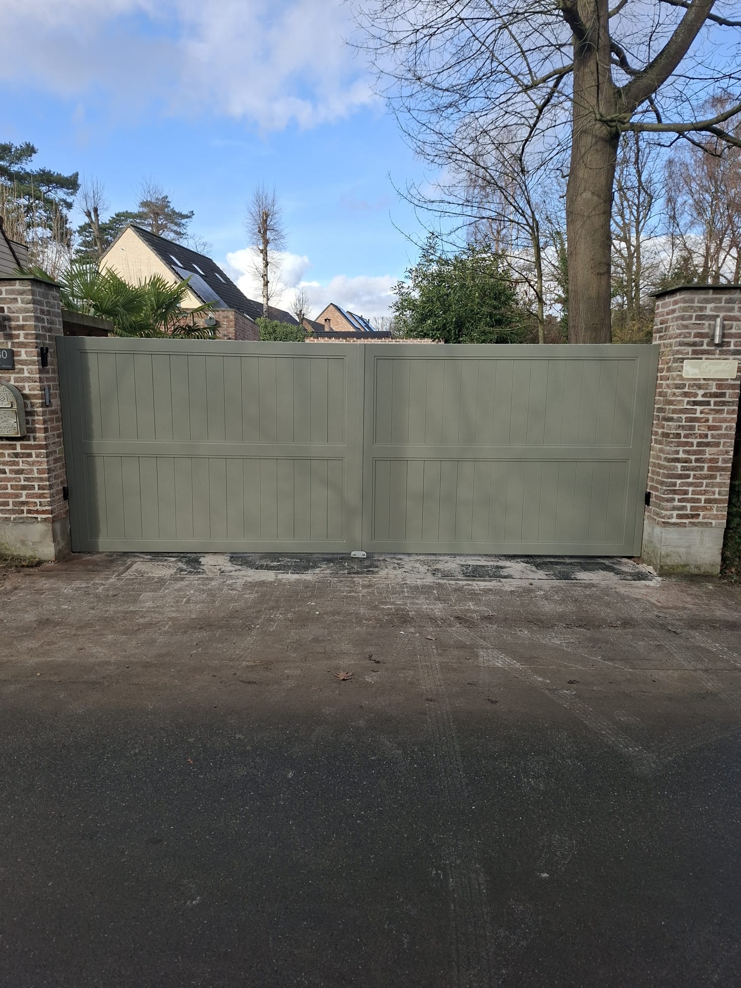 Saliegroene paneelpoort tussen stenen kolommen