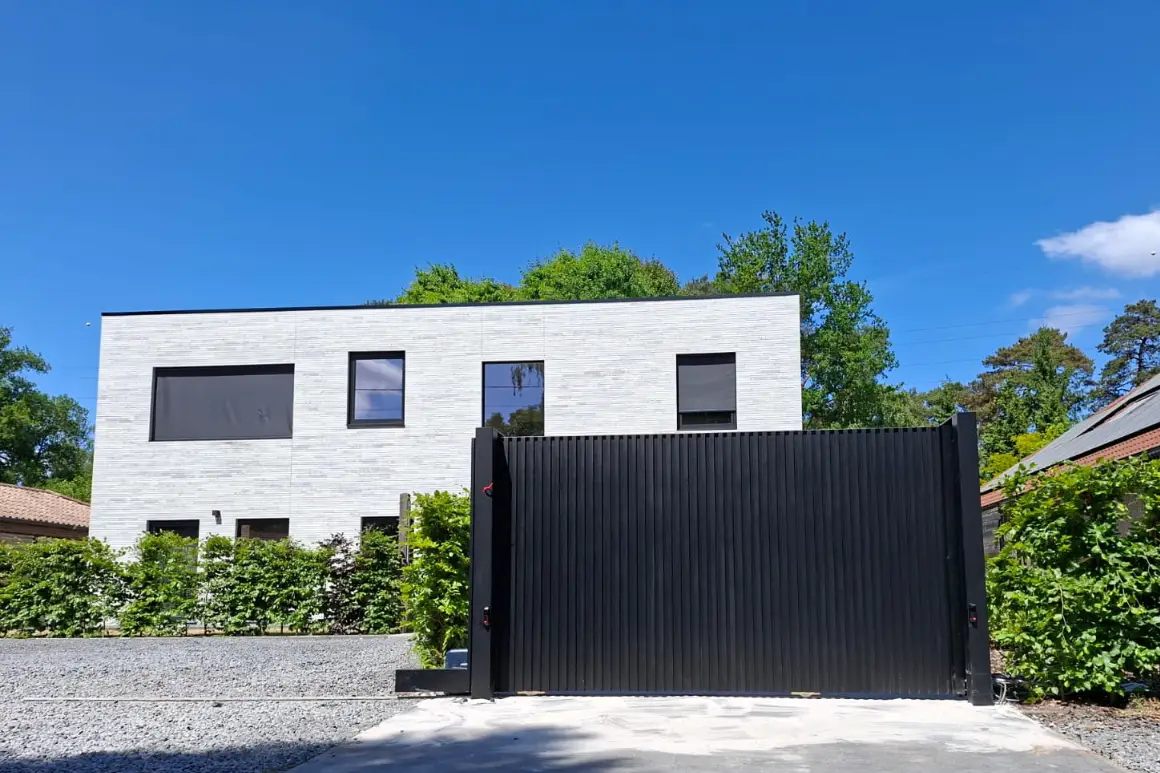 Zwarte schuifpoort met verticale lamellen voor moderne witte woning