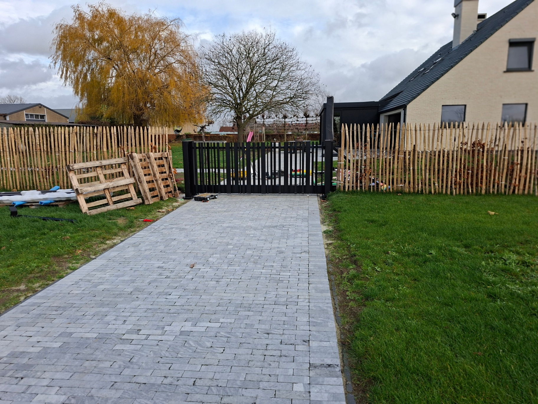 Zwarte dubbele draaipoort met verticale spijlen in tuin
