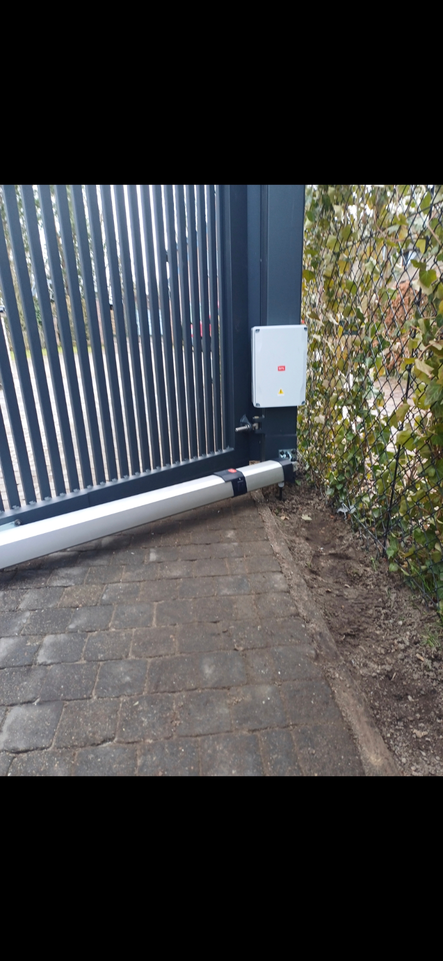 Detail van BFT stuurkast en motor op antracieten poort
