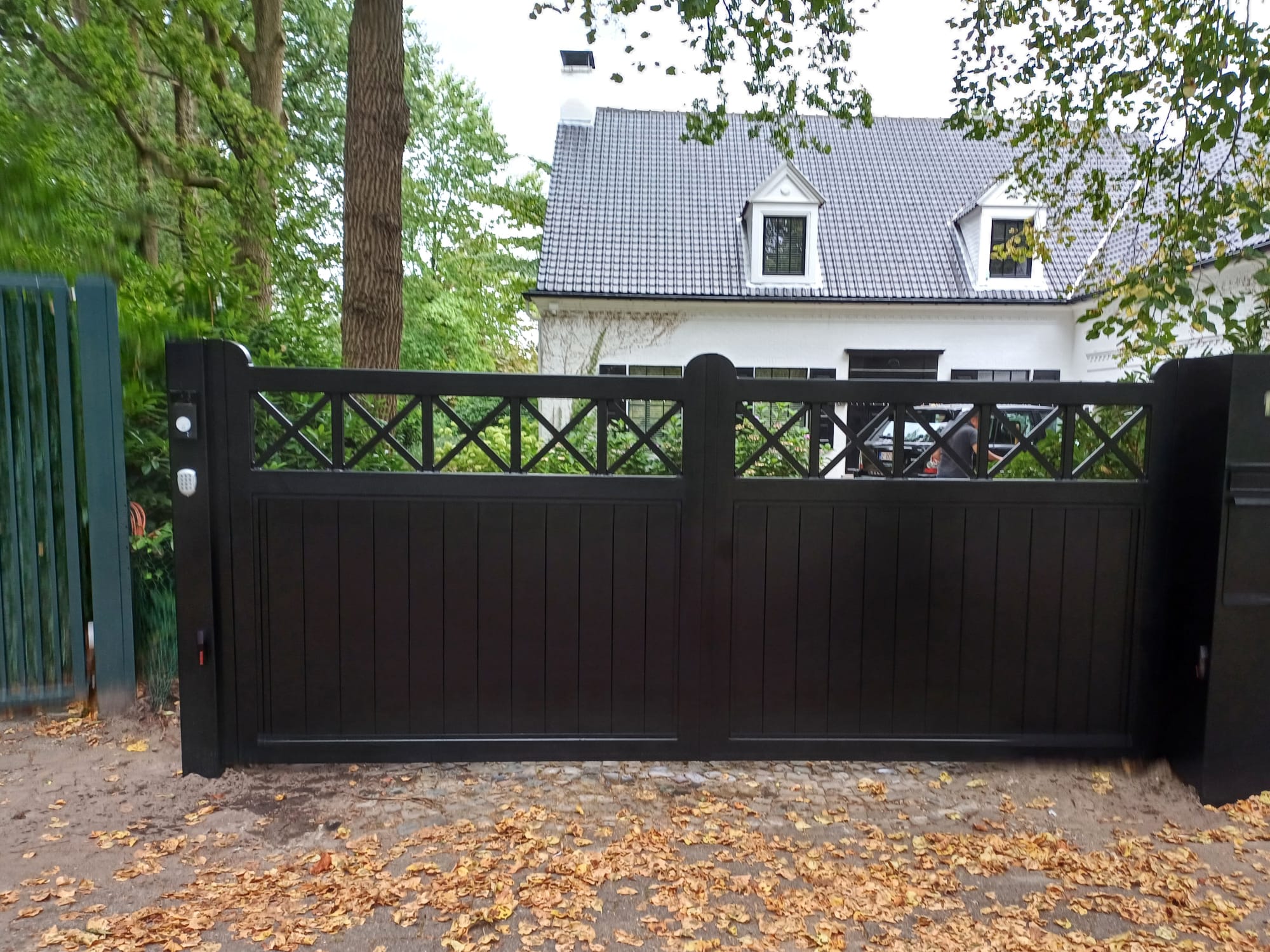 Zwarte poort met kruismotief bij witte woning
