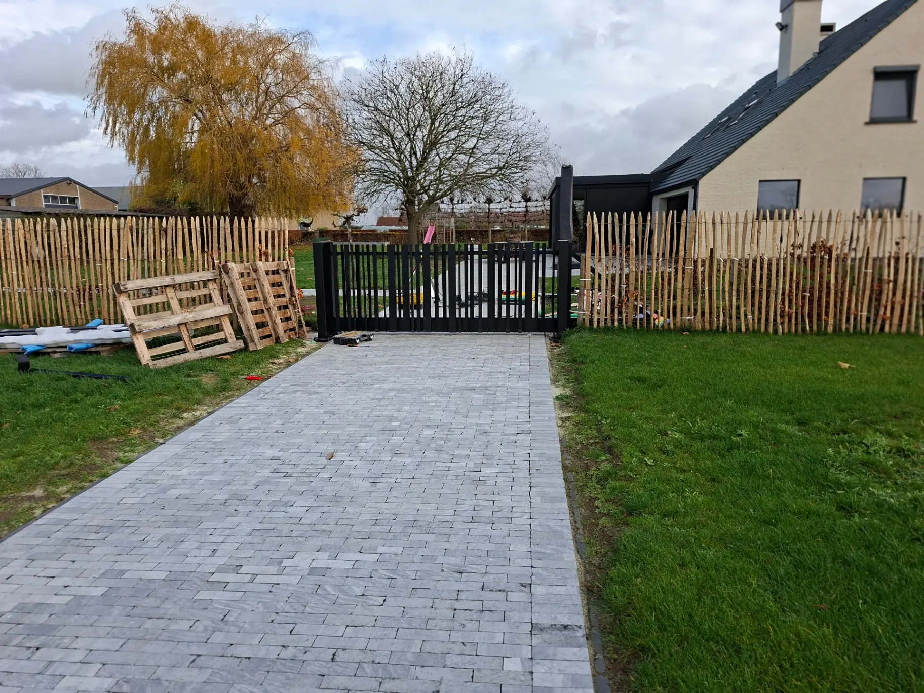 Zwarte schuifpoort met verticale lamellen in tuin